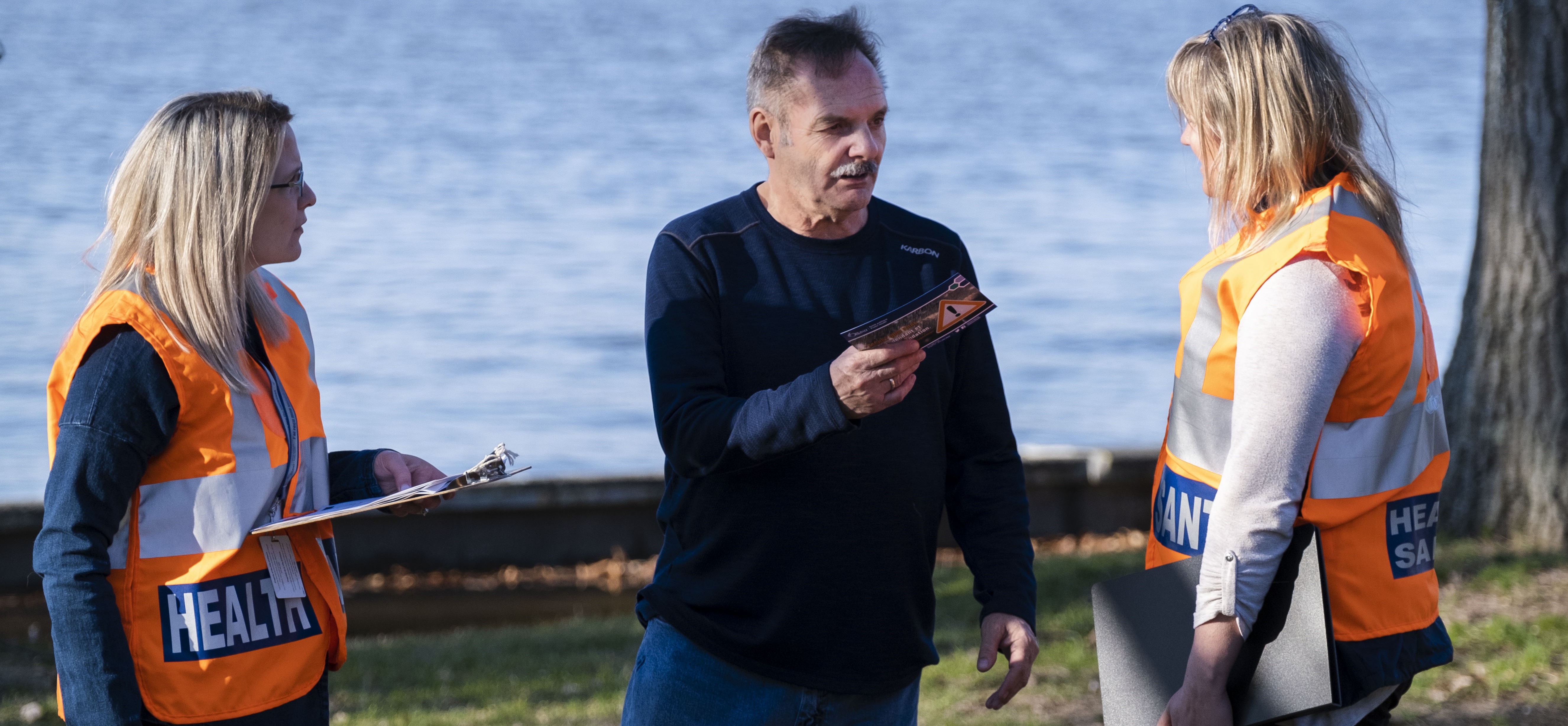 A man speaking to two public health staff
